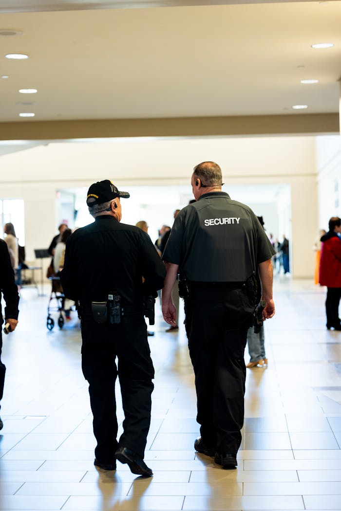Two security guards walking indoors, ensuring safety in a busy public space.